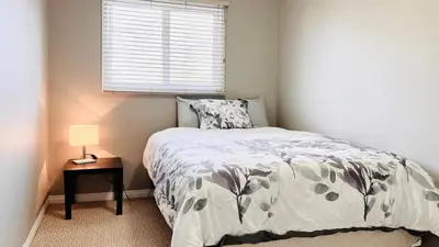 a bedroom with a bed and a lamp and a window at Lovely 2 Bedroom apartment in Camrose