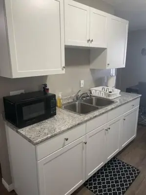 a kitchen with white cabinets and a sink and a microwave at Lovely 2 Bedroom apartment in Camrose