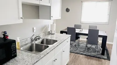a kitchen with a sink and a table with chairs at Lovely 2 Bedroom apartment in Camrose