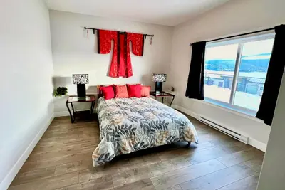 a bedroom with a bed with red pillows and a window at Kelowna new lake view 2bedrooms close BIG WHITE in Kelowna