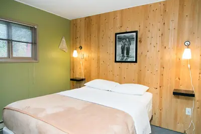 a bedroom with a bed and a wooden wall at Lone Star Motel in Rossland