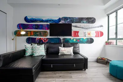 a living room with a black couch and skateboards on the wall at The Après, Village Studio with Hot Tub and View in Whistler