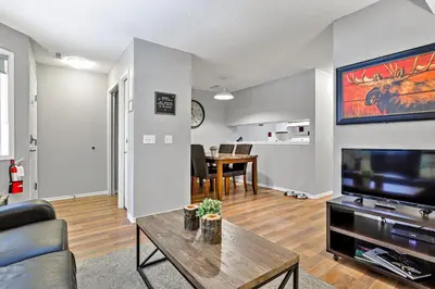 a living room with a couch and a tv and a table at The Norquay, Pet-Friendly 2 Bed with Mtn View in Canmore