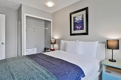 a bedroom with a large white bed with a blue blanket at The Norquay, Pet-Friendly 2 Bed with Mtn View in Canmore