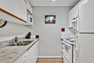 a white kitchen with a sink and a refrigerator at The Norquay, Pet-Friendly 2 Bed with Mtn View in Canmore