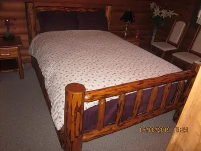 a bed in a room with a wooden frame at Kamloops Log Home Bed and Breakfast in Kamloops
