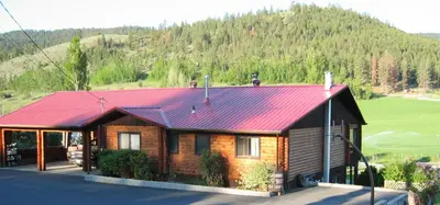a log cabin with a red roof on a mountain at Kamloops Log Home Bed and Breakfast in Kamloops