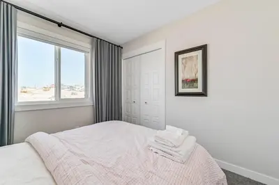 a white bedroom with a bed and a window at Brand New 3-Bedroom Home in a Quiet Neighborhood in Calgary