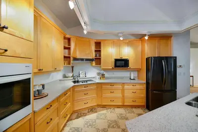 a kitchen with wooden cabinets and a black refrigerator at Beachside Living Cherry Point by EMR Vacation Rentals in Cobble Hill
