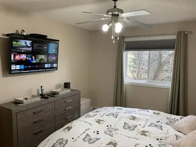 a bedroom with a bed and a television on the wall at Chris Cozy Condo Commonwealth #205 Edmonton in Edmonton