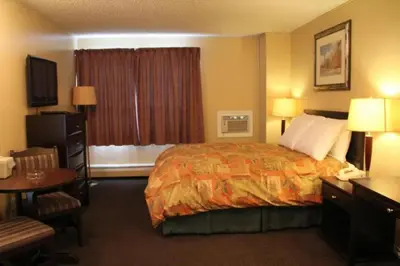 a hotel room with a bed and a desk and a table at Acorn Motel in Grande Cache