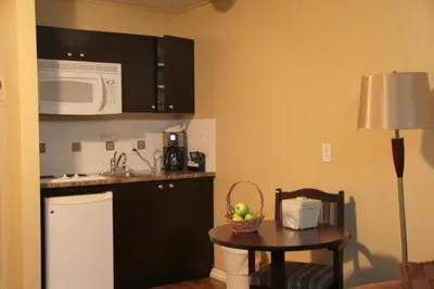 a kitchen with a small table and a microwave at Acorn Motel in Grande Cache