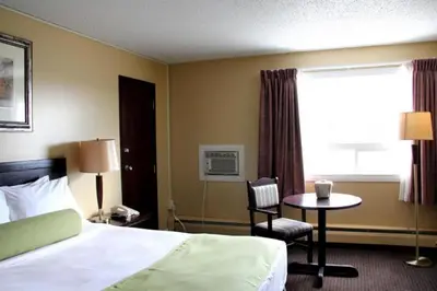 a hotel room with a bed and a table and a window at Acorn Motel in Grande Cache