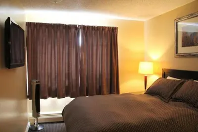 a hotel room with a bed and a window at Acorn Motel in Grande Cache