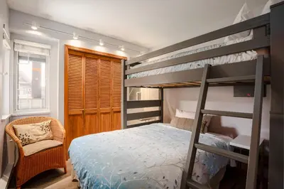 a bedroom with two bunk beds and a chair at 3BR in Sunpath, King Bed, Village Location, Private Patios, Hot Tub and Pool in Whistler