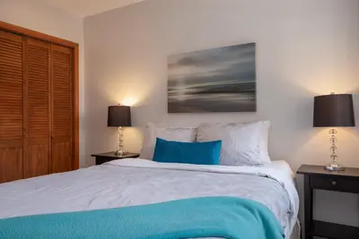 a bedroom with a large bed with blue pillows at 3BR in Sunpath, King Bed, Village Location, Private Patios, Hot Tub and Pool in Whistler