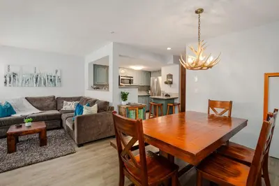 a dining room and living room with a wooden table at 3BR in Sunpath, King Bed, Village Location, Private Patios, Hot Tub and Pool in Whistler