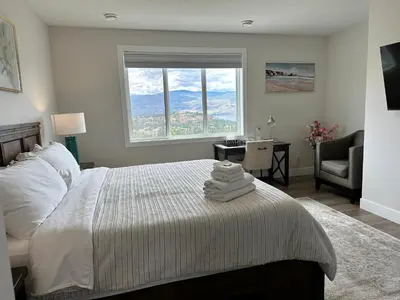 a bedroom with a bed with a window and a chair at Shannon Heights B&B in West Kelowna