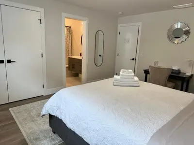a white bedroom with a large bed with a mirror at Shannon Heights B&B in West Kelowna