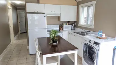 a kitchen with white cabinets and a table with a plant on it at Private Suite w King Bed, Ground Level, Naturally Bright in Vancouver