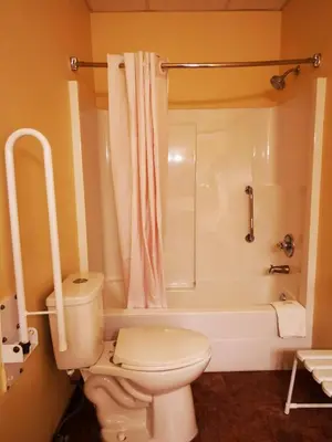 a bathroom with a toilet and a shower and a tub at MountainView Hotel Merritt in Merritt