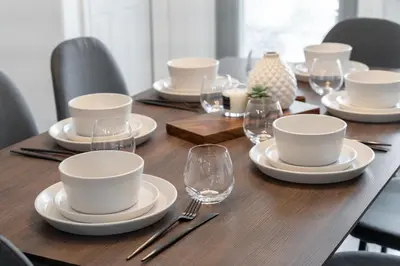 a wooden table with plates and wine glasses on it at Dino Roar I Sleeps 12 I New in Drumheller