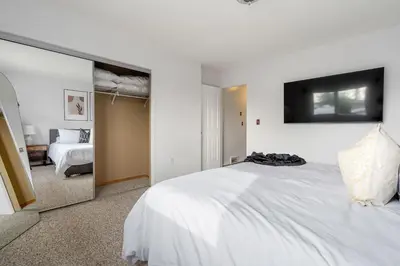 a bedroom with a large white bed and a mirror at Dino Roar I Sleeps 12 I New in Drumheller