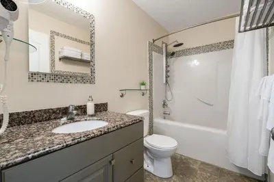 a bathroom with a sink and a toilet and a tub at Dino Roar I Sleeps 12 I New in Drumheller
