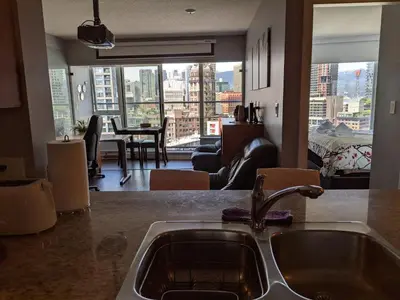 a kitchen with a sink and a view of a living room at Vancouver Downtown Accommodation in Vancouver