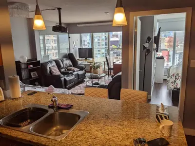 a kitchen with a sink and a living room at Vancouver Downtown Accommodation in Vancouver