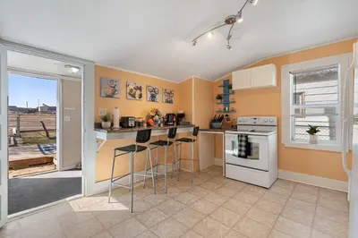 a kitchen with orange walls and a counter with stools at Dino Cave l Walk to Downtown l Fire Pit & BBQ I TV in Drumheller