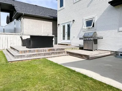 a backyard with a grill and steps to a house at LUXURIOUS 6 Bed Home I Fireplace I near Sports Park I with Double Garage & Fast WiFi! in Edmonton
