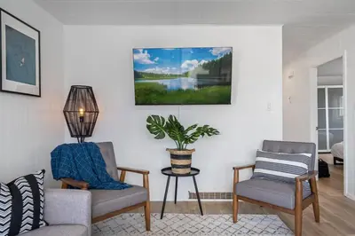 a living room with two chairs and a potted plant at The Hidden Loft I 5-min Walk 2 Beach I DT I 55 TV in Sylvan Lake
