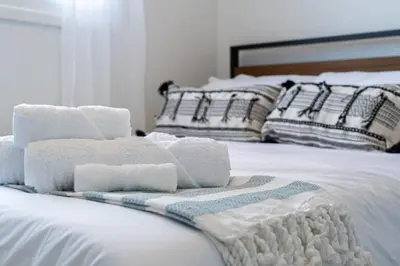 a pile of towels sitting on top of a bed at The Hidden Loft I 5-min Walk 2 Beach I DT I 55 TV in Sylvan Lake