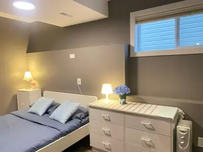 a bedroom with a bed with a dresser and a window at lovely home in Calgary