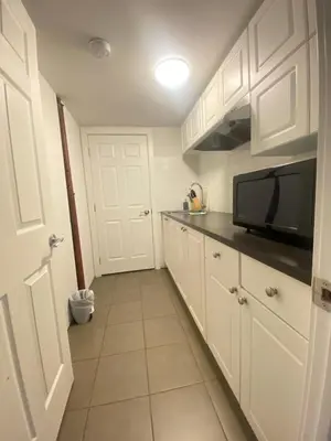 a small kitchen with white cabinets and a microwave at lovely home in Calgary