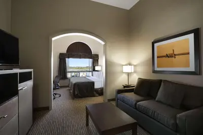 a hotel room with a bed and a living room with a couch at Ramada by Wyndham Conklin in Conklin