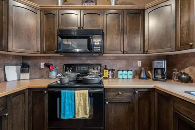 a kitchen with wooden cabinets and a stove top oven at Prairie Oasis I Sleeps 16 l BBQ & Patio l Smart TV in Sylvan Lake