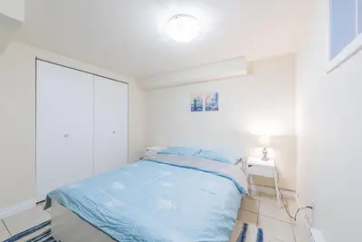 a white bedroom with a blue bed and a lamp at UofC-SAIT-Banff Trail-Suite A&B in Calgary
