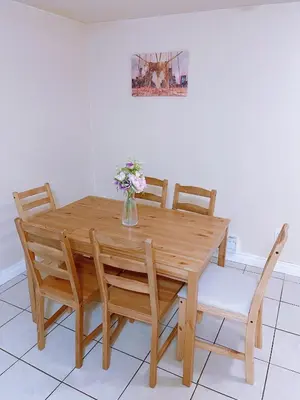 a wooden table with chairs and a vase with flowers at UofC-SAIT-Banff Trail-Suite A&B in Calgary