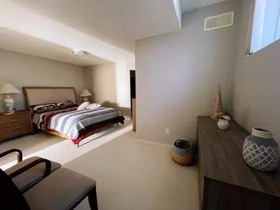 a bedroom with a bed and a chair in it at Spacious and quiet garden view room in Kelowna