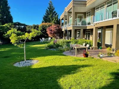 a building with a yard with a tree and a table at Spacious and quiet garden view room in Kelowna