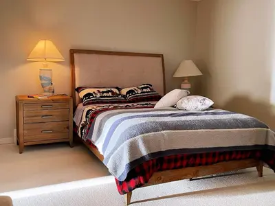 a bedroom with a bed and a nightstand with two lamps at Spacious and quiet garden view room in Kelowna