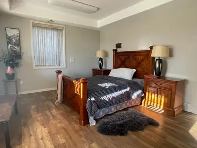 a bedroom with a bed and a rug on the floor at Spacious and quiet garden view room in Kelowna