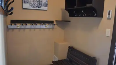 a room with a bench next to a wall with lights at Stones Throw #24 in Sun Peaks