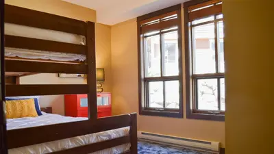 a bedroom with two bunk beds and two windows at Stones Throw #24 in Sun Peaks