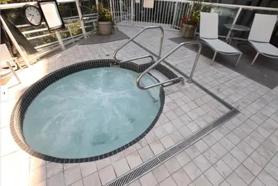 a hot tub on a patio with chairs and a clock at Ski-in Ski-out at upper village next to Fairmount Hotel In Whistler in Whistler