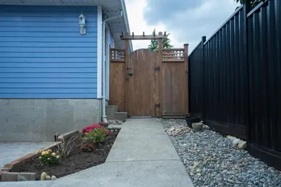 a backyard with a blue house and a fence at Lovely 1BR Secondary suite with Separate entrance in New Westminster