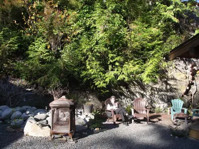 a woman sitting on a bench in a garden at Wild Coast Chalets in Port Renfrew