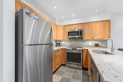 a kitchen with a stainless steel refrigerator and wooden cabinets at 3BR in Whistler Creek Ridge, Ski In, Ski Out, Private Hot Tub, Wood Burning Fireplace, Private Garage in Whistler